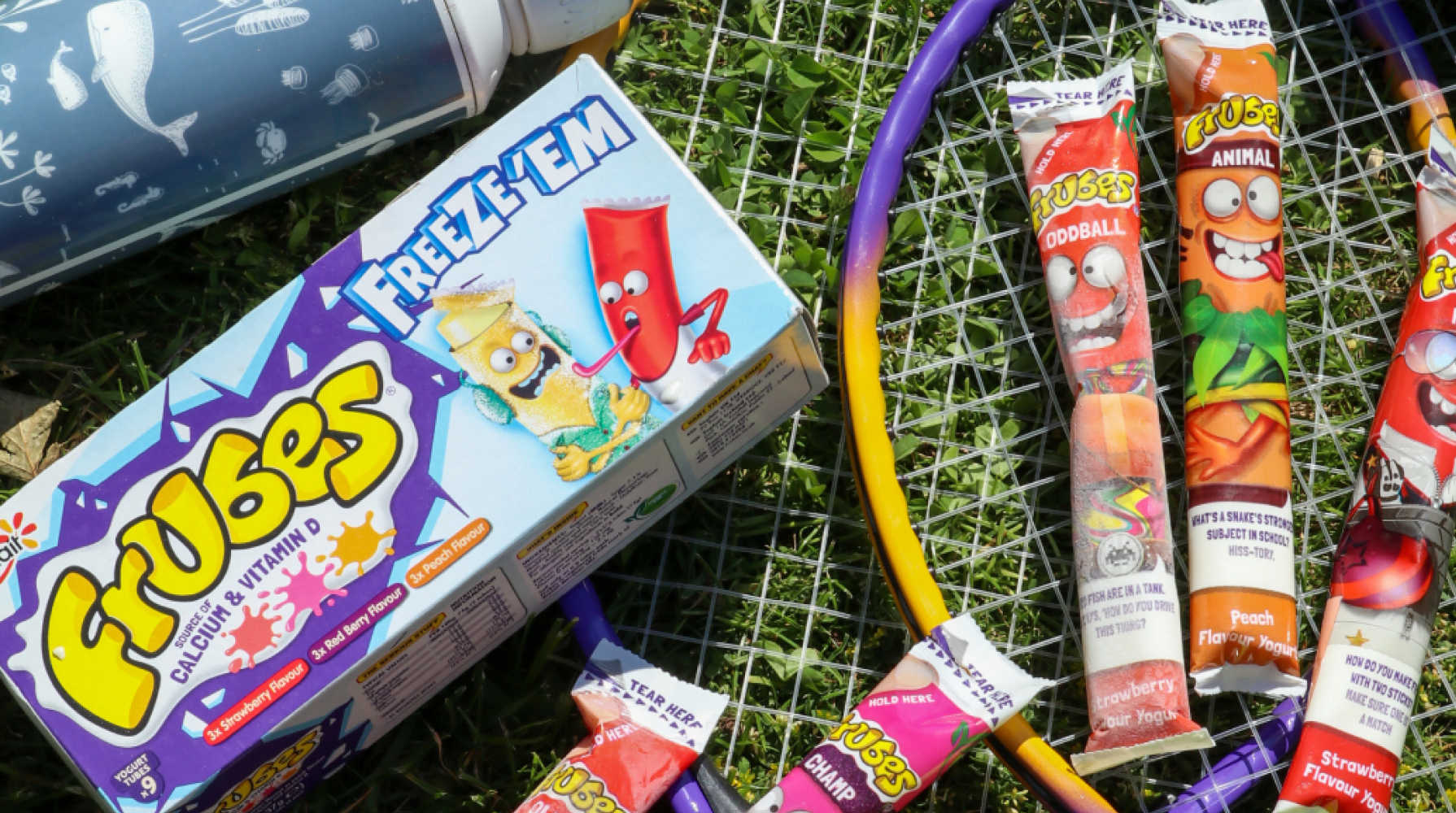 A Frubes multipack box and several individual yoghurt tubes are shown on grass.