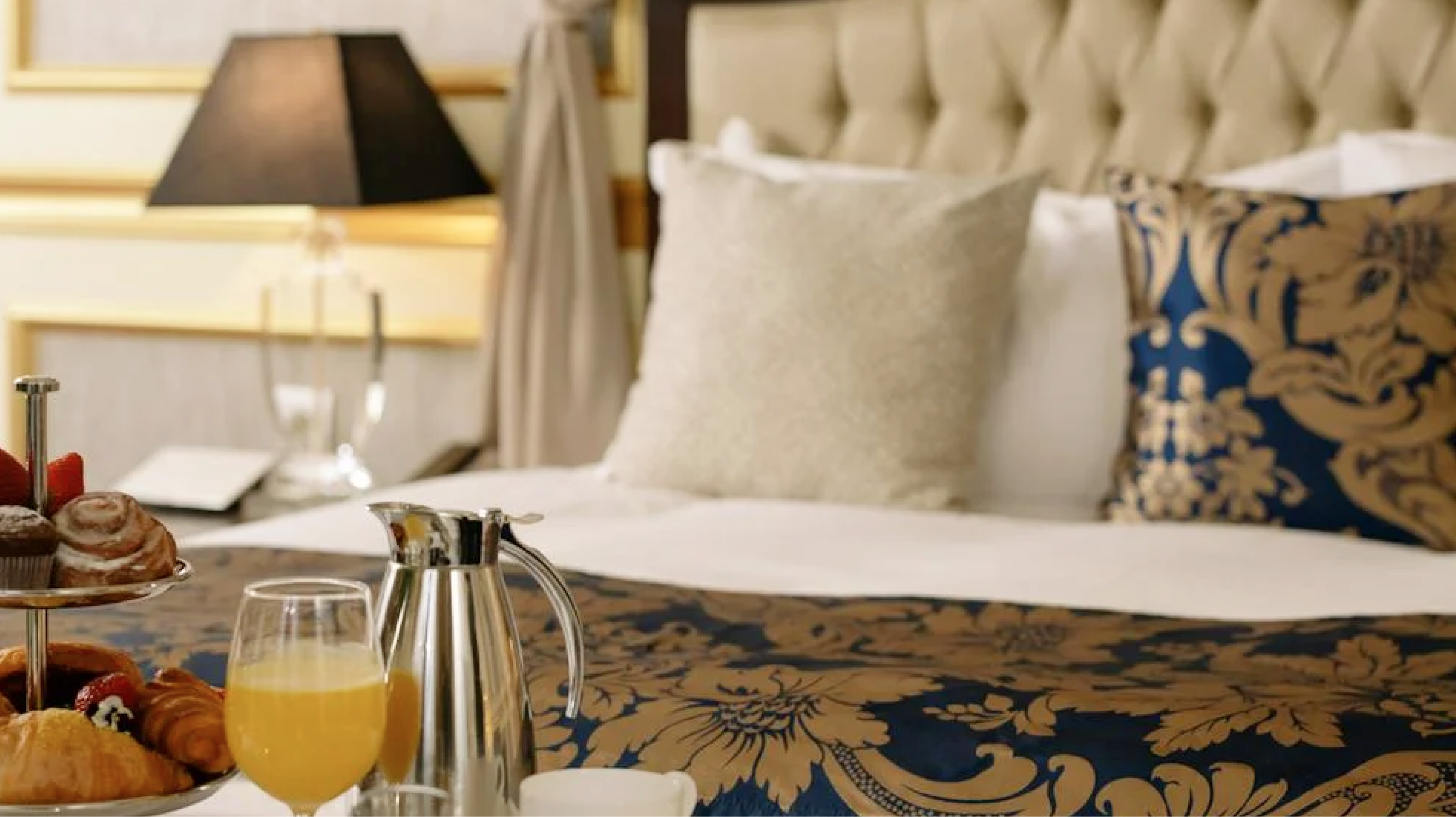 Breakfast placed in front of a bed at a luxurious hotel room.
