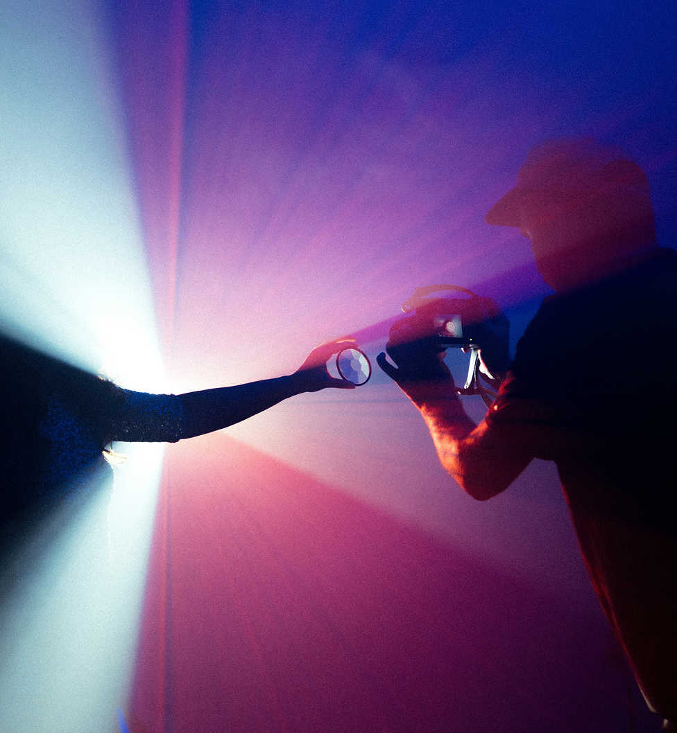 Silhouetted scene of a person filming with dramatic, colourful lighting