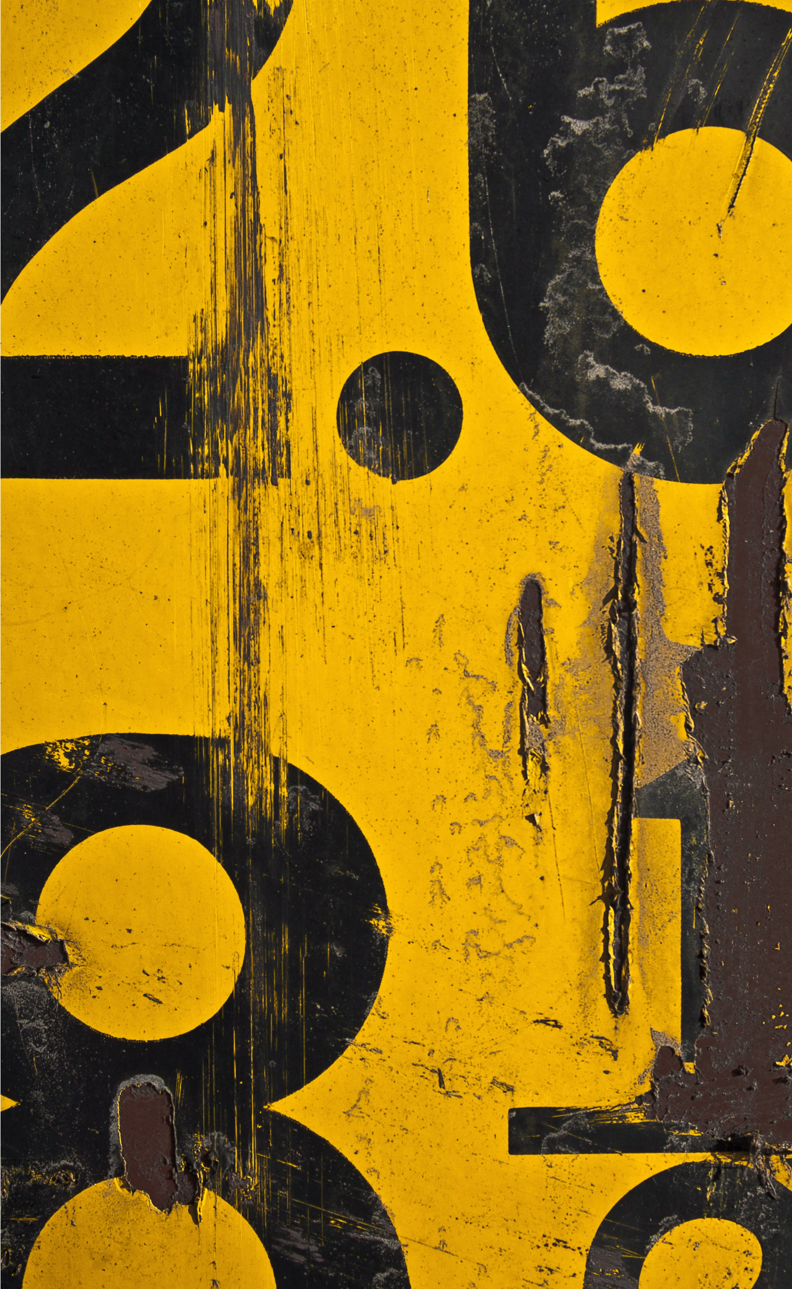 Close-up of a weathered yellow surface with partially visible black numbers and dots, showing signs of rust, scratches, and peeling paint.