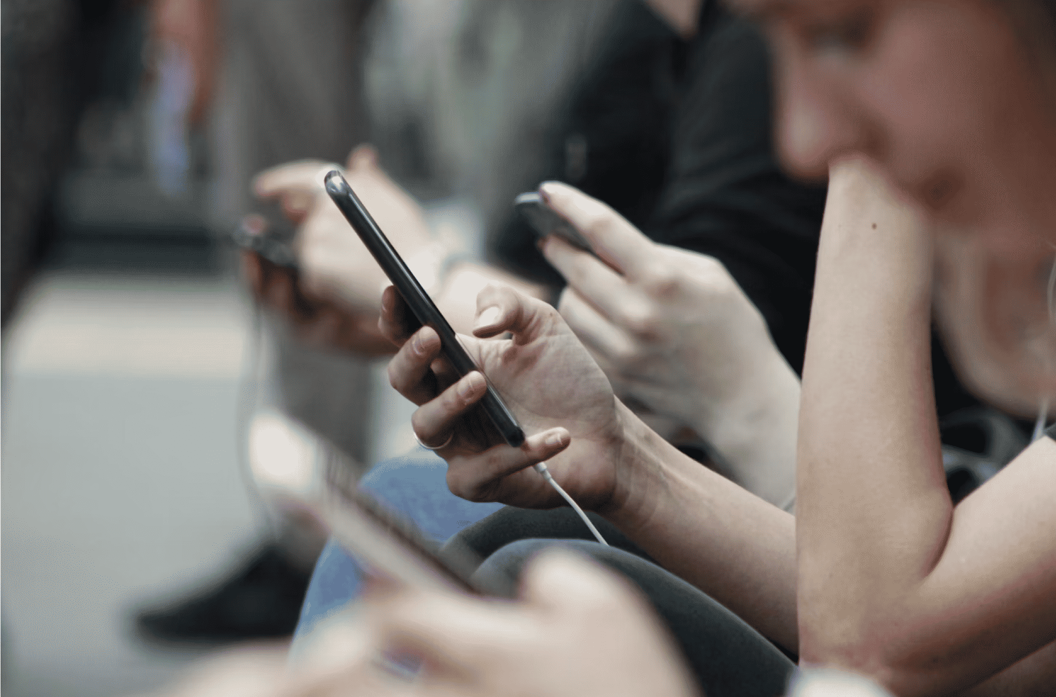 A group of people sitting in a row, each using a smartphone.