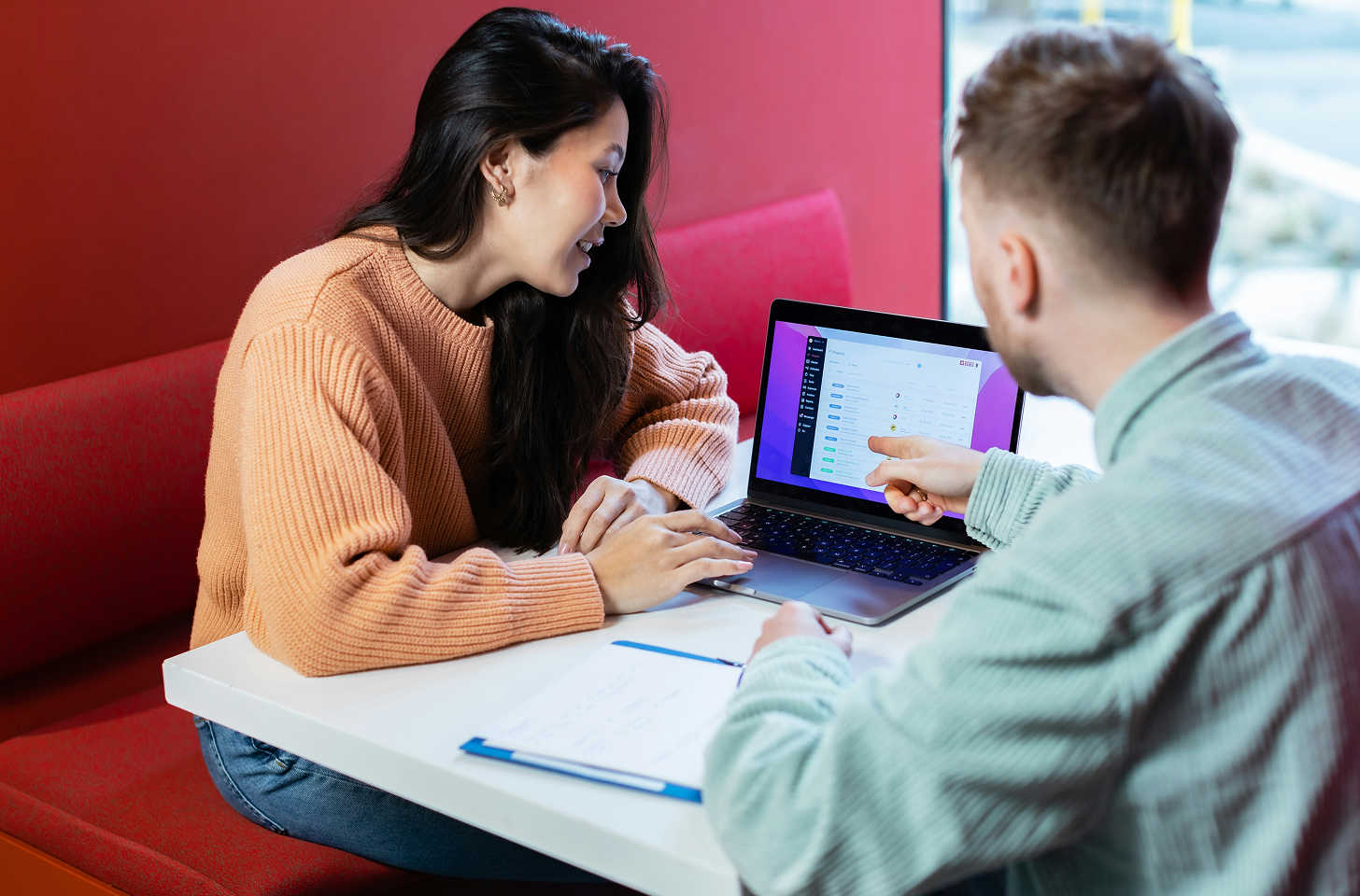 Two people siting at a laptop together pointing at the screen