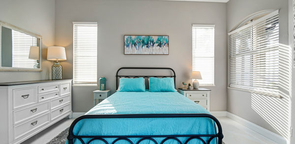 Bedroom With White Blind Curtains and Double Bed Covered in Sky Blue Bedding