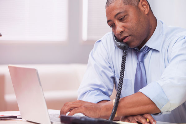 Man using enterprise VoIP solution with his office desk phone