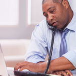 man-using-enterprise-voip-with-his-desk-phone.png