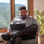 Man looking at laptop from home enjoying 8x8 99.999% uptime SLA