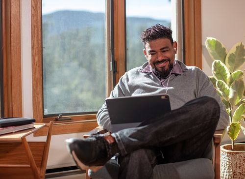 Man looking at laptop from home enjoying 8x8 99.999% uptime SLA