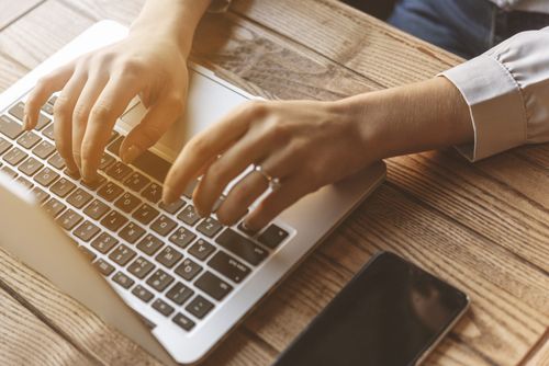 Woman's hands typing on laptop keyboard