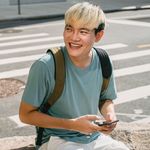 A boy with dyed hair sending an SMS message on his mobile phone