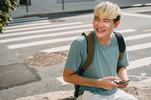 Man smiling while texting on his phone