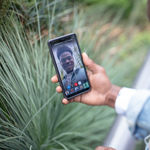 Man outdoors using 8x8 video conferencing solutions on his smartphone to collaborate with teammate