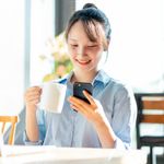 Woman at desk smiling while using her phone