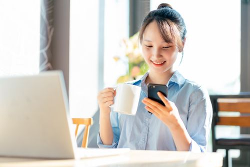 Woman at desk smiling while using her phone