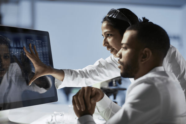 Two advisors trying to analyze data on customer requests on a computer screen.