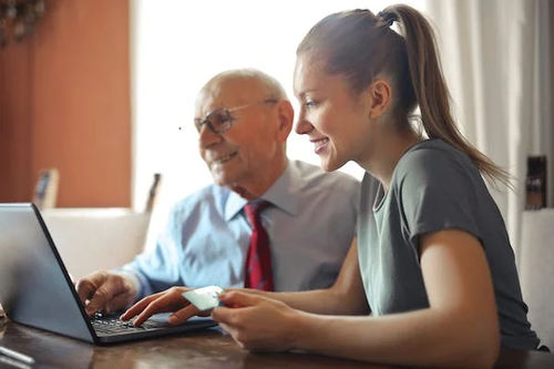 A girl and an old man filling customer experience form on laptop