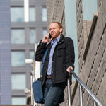 Man on outdoor stairs using mobile phone to access small business phone system