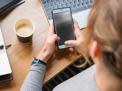 A lady sending an SMS message on her mobile in the office