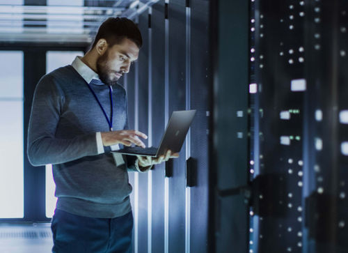 8x8 employee using laptop in data center server room initiating secure cloud migration