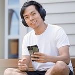 Man smiling with headphones on while holding a phone