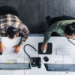 Two employees sitting on their work stations making calls via VoIP phone service