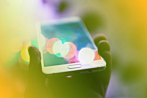 Internet phone service represented as a hand holding up a mobile phone with colorful lights around it