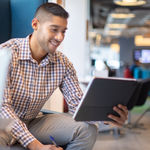 A seated man reading about 8x8 partner program’s features on a tab