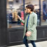 Woman walking on sidewalk checking 8x8's service status on her phone