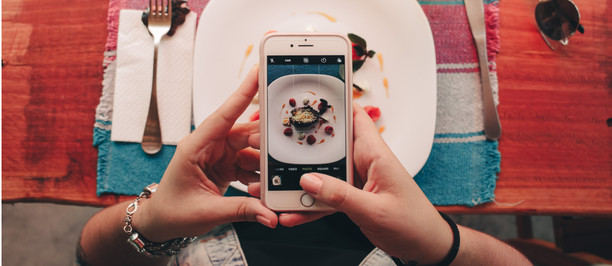 A girl takes a picture of her dinner with her smartphone.