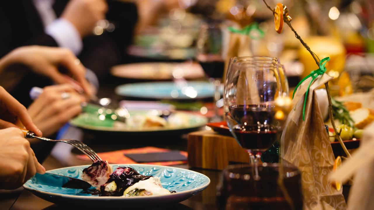 A restaurant table with a glasses of wine and different plates with dishes.