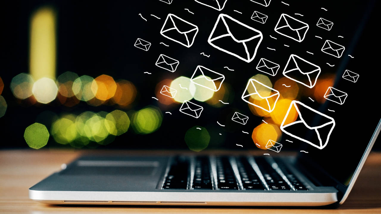 A laptop is placed on the table and various icons of email are shown on it.