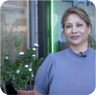 A middle-aged woman smiling and staring at somewhere.