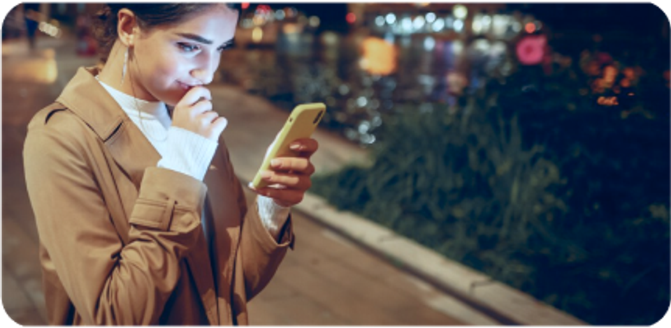 A young girl is looking at her smartphone in the street.