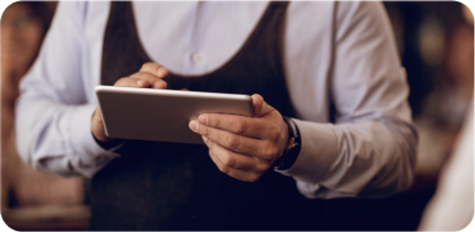 A waiter is working with a tablet.