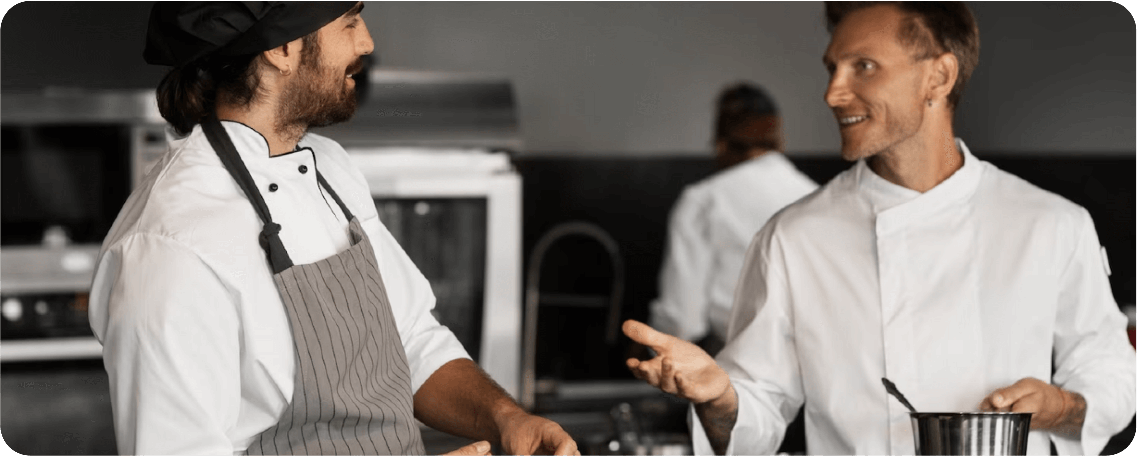 Two cooks are talking to each other in the kitchen.