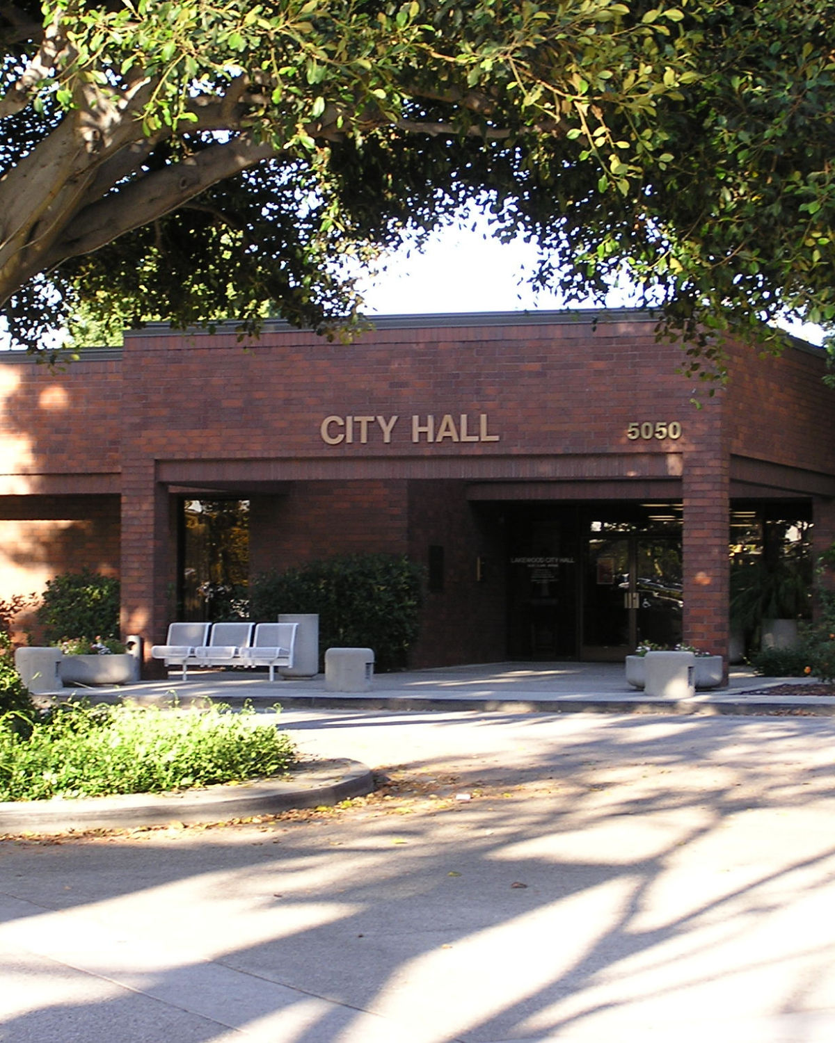 Lakewood City Hall, a brick civic building surrounded by trees with a clear sky overhead.