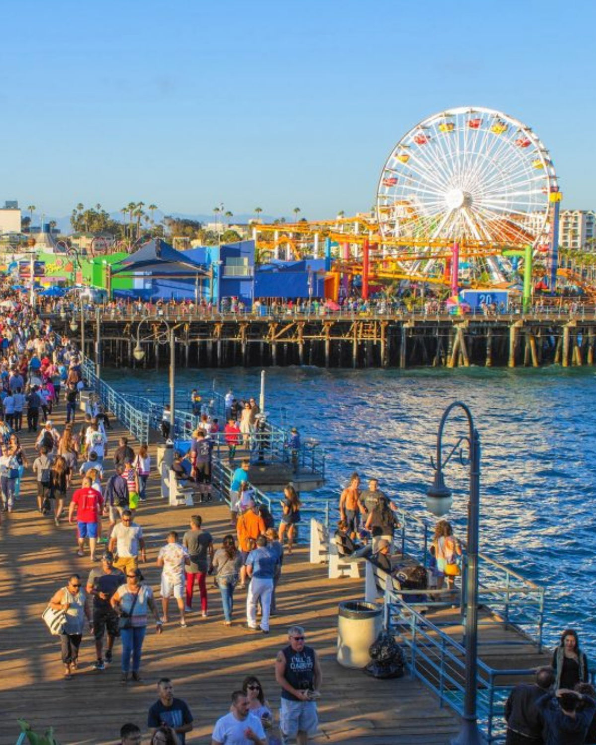 The Venice Beach Boardwalk with street performers, shops, and the ocean just beyond the promenade.