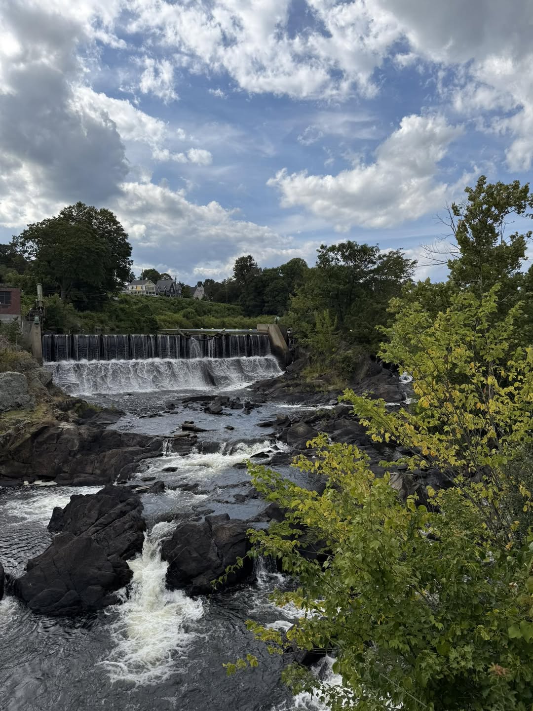 A scenic waterfall and rushing river in Putnam, Connecticut, surrounded by rocky terrain and lush greenery, showcasing the town’s natural beauty and peaceful New England outdoor charm.