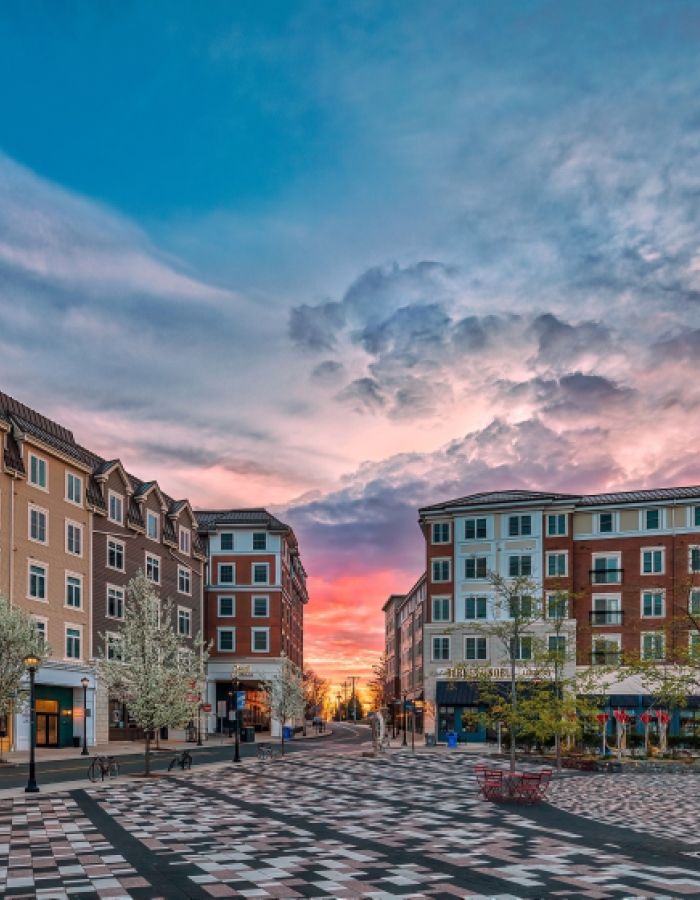 Downtown Storrs Center in Mansfield, Connecticut at sunset, featuring modern mixed-use buildings, brick walkways, outdoor gathering spaces, and the vibrant heart of the UConn community.