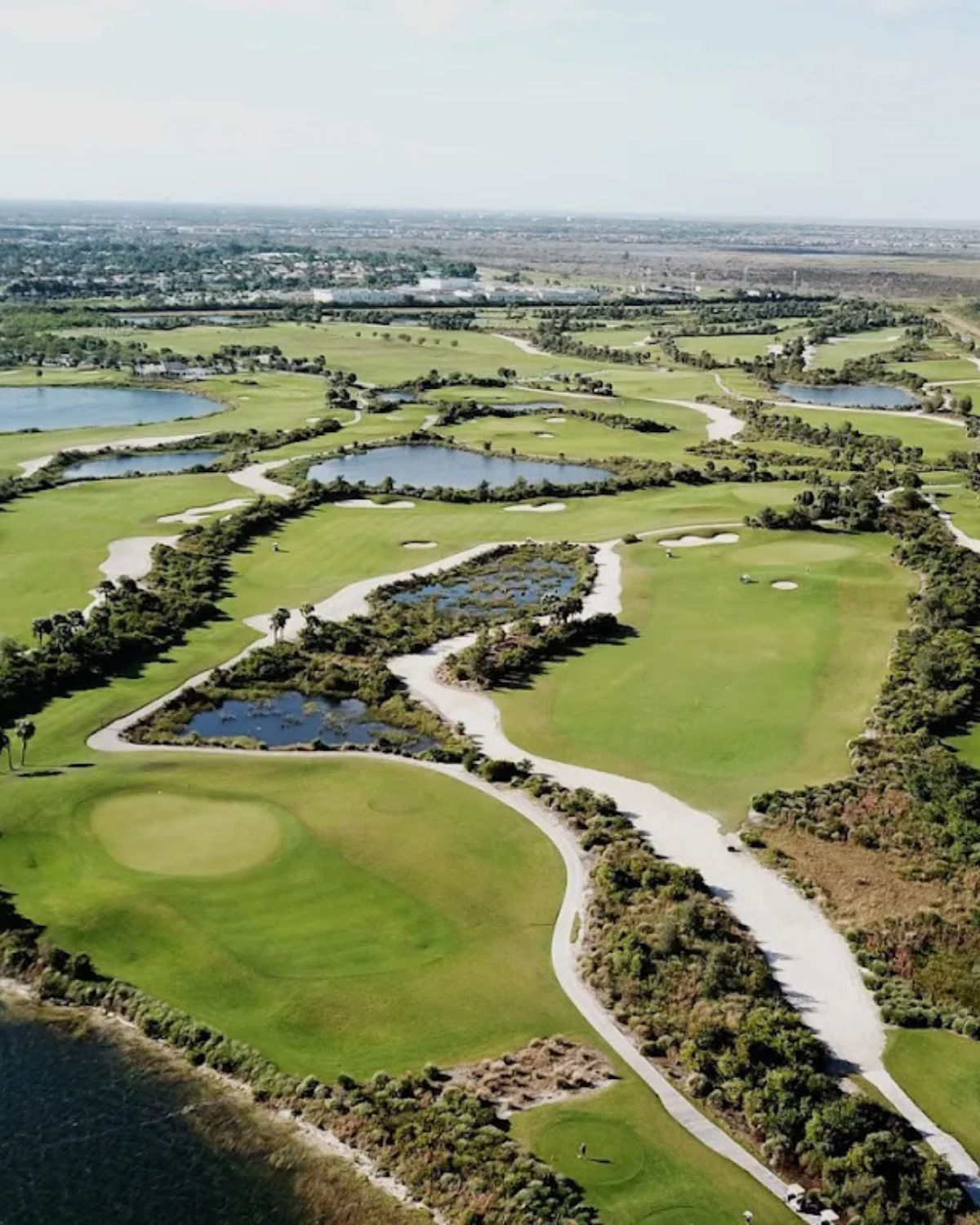 Aerial view of Osprey Point Golf Course in South Florida, with wide green fairways, winding  cart paths, and numerous water hazards and ponds