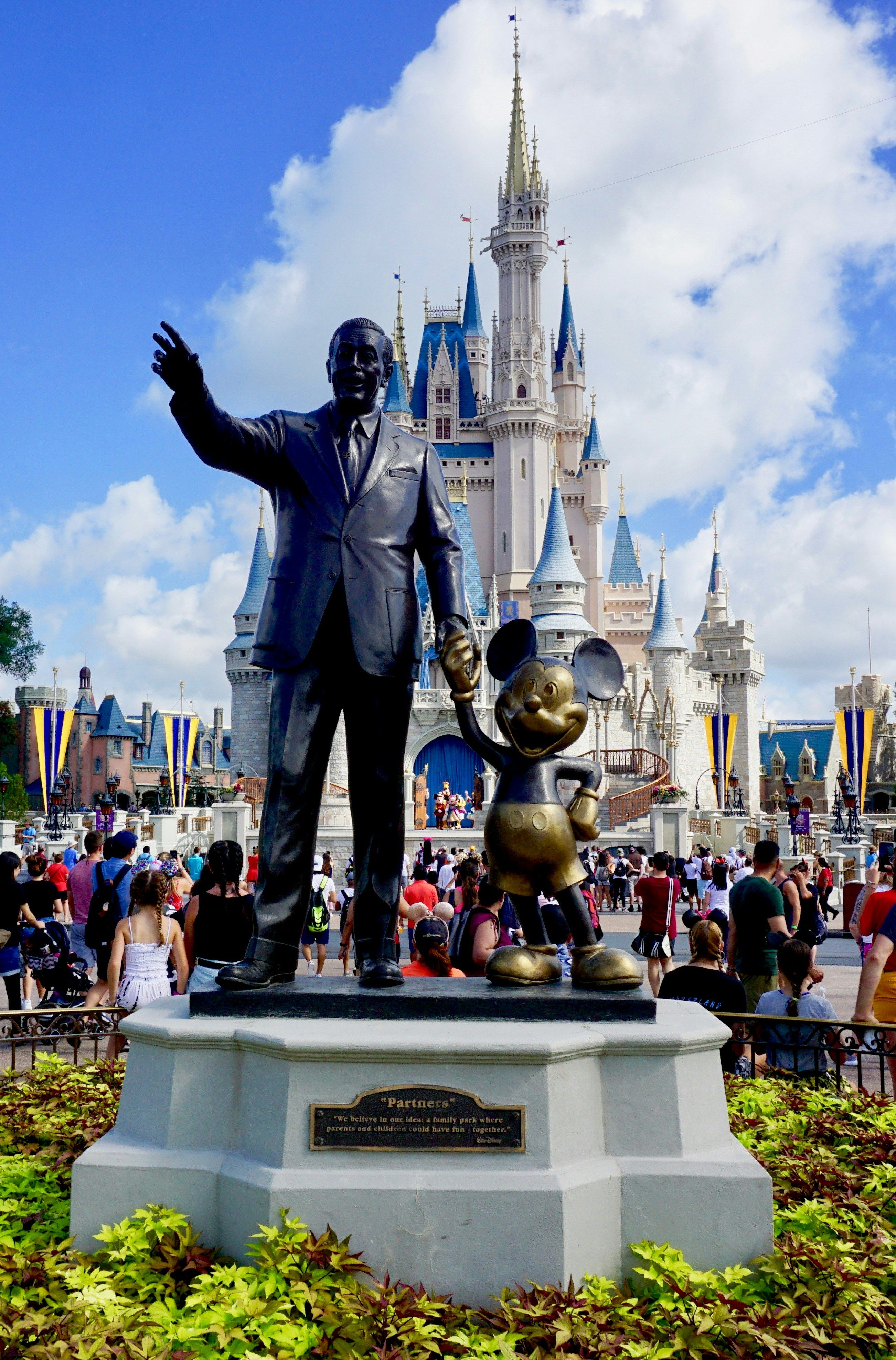 Walt Disney World's Cinderella Castle with the iconic Mickey and Walt Disney Partners statue in the foreground
