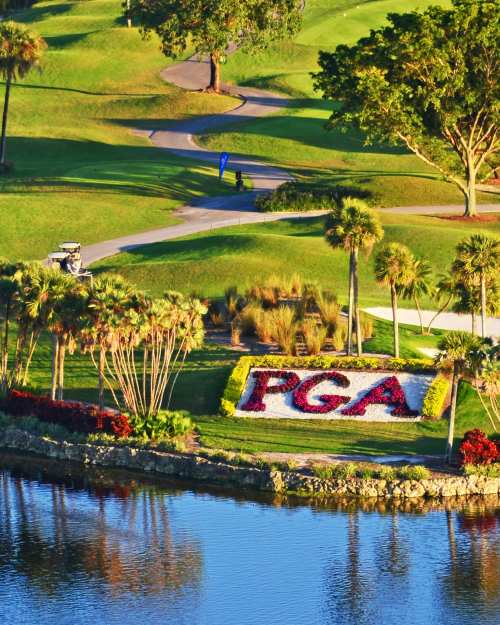 Lush green fairways at PGA National Golf Club in Palm Beach Gardens with PGA floral signage