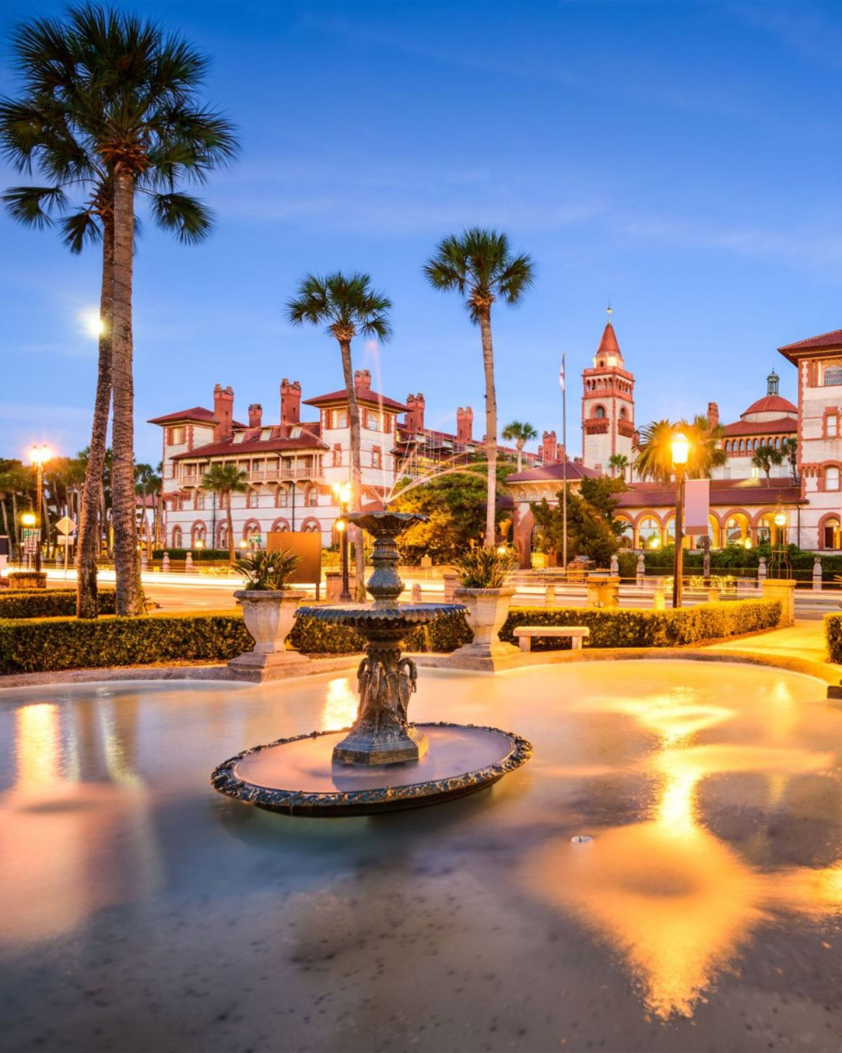 The illuminated historic Flagler College building and Lightner Museum glowing at dusk on the plaza in downtown Saint Augustine, Florida