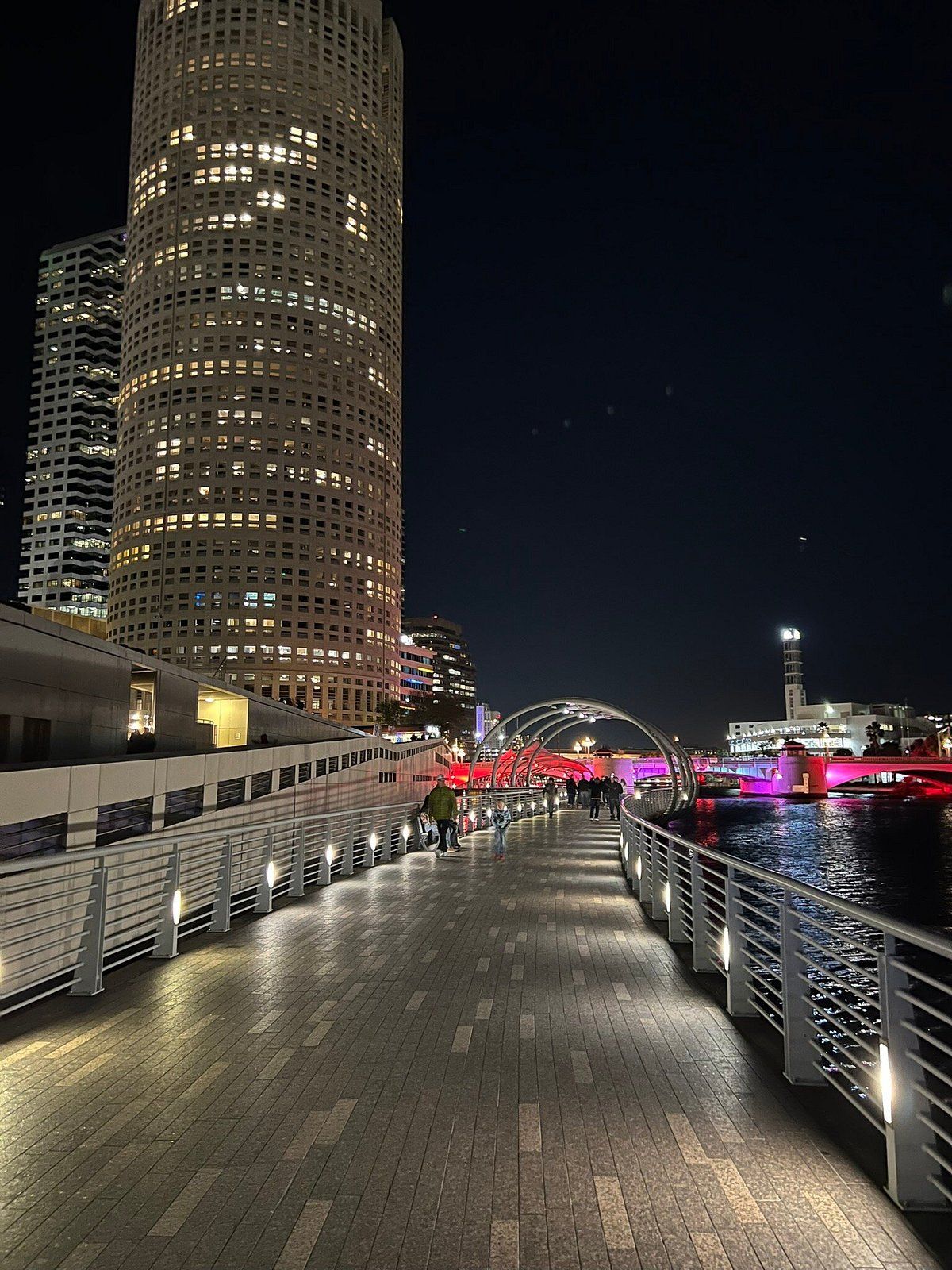 Tampa, Florida riverwalk at night with illuminated high-rise buildings reflecting on the water