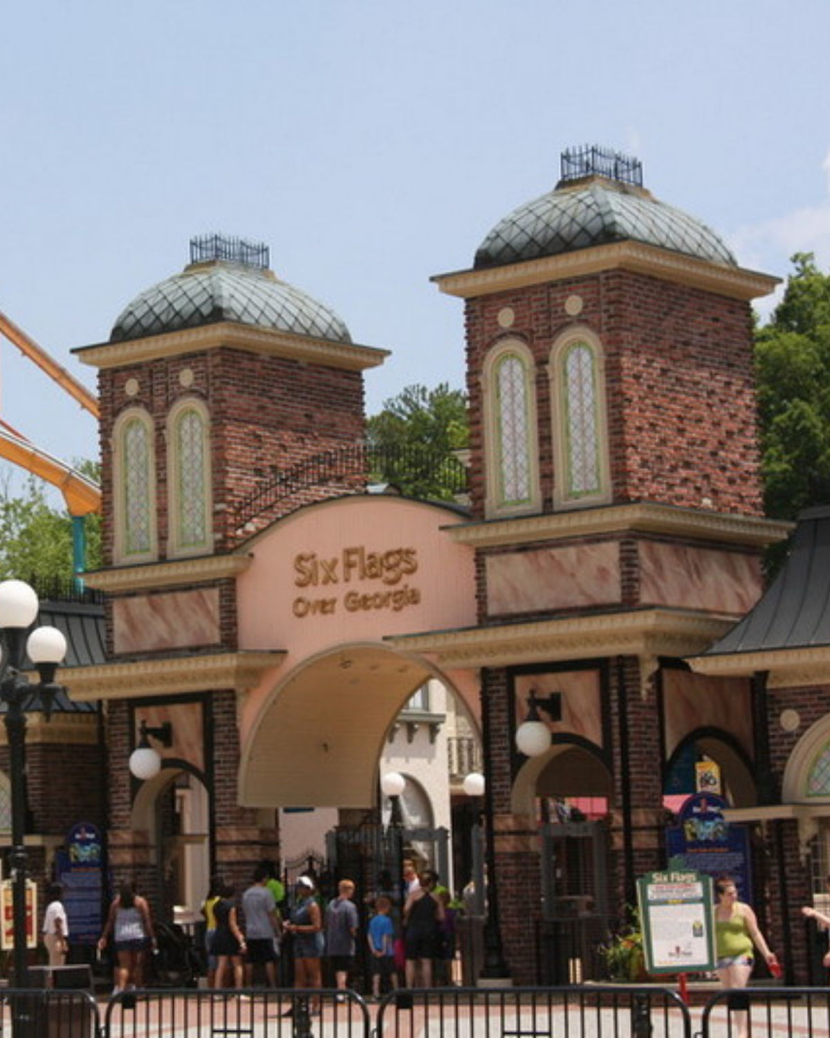 Main entrance to Six Flags Over Georgia in Austell, Georgia, showing the arched gateway with ŇSix Flags Over GeorgiaÓ and two brick towers as guests walk through the plaza beneatha nearby coaster