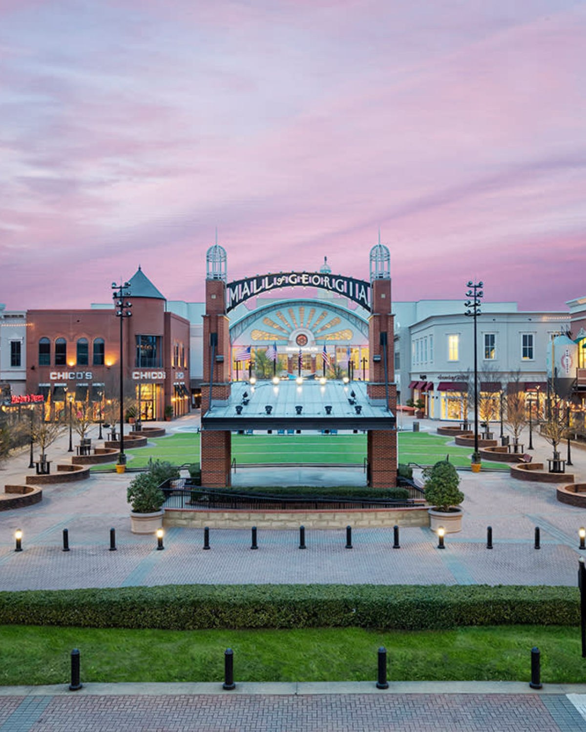 Village Amphitheatre at the Mall of Georgia in Buford, Georgia, showing the open plaza framed by shops and a brick structure with with the illuminated ŇMall of GeorgiaÓ arch