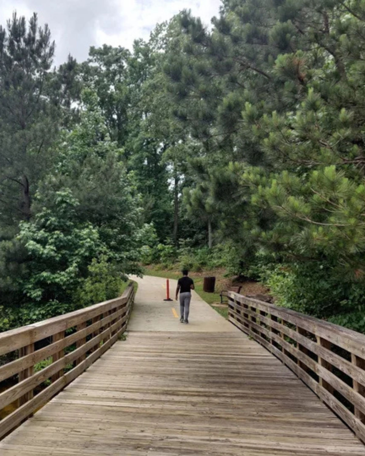 Wooden pedestrian bridge and paved walking trail at Riverdale Regional Park in Riverdale, Georgia, surrounded by trees
