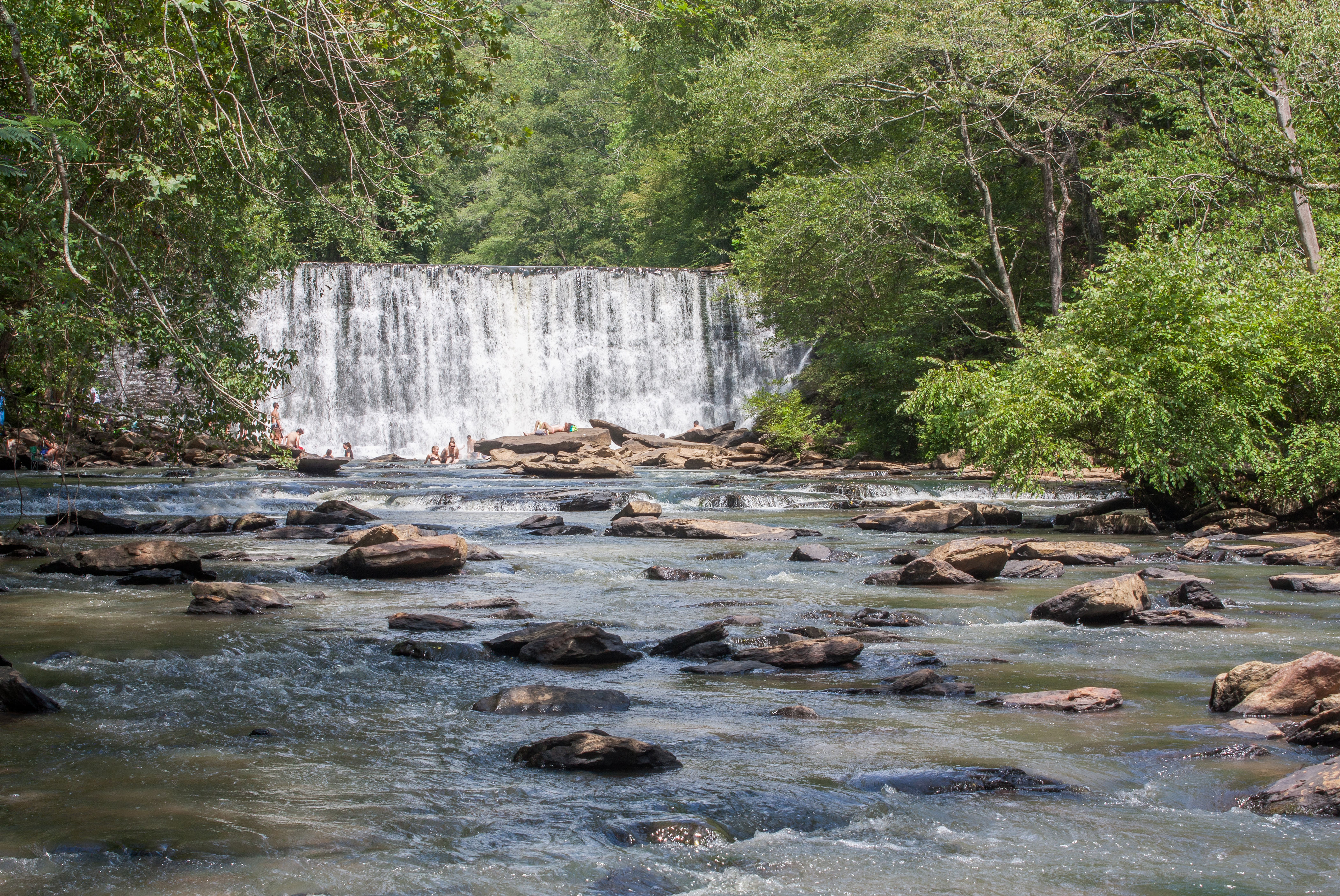Rocky creek with cascading waterfall flowing through lush green forest at Vickery Creek and Roswell Mill in Roswell, GA