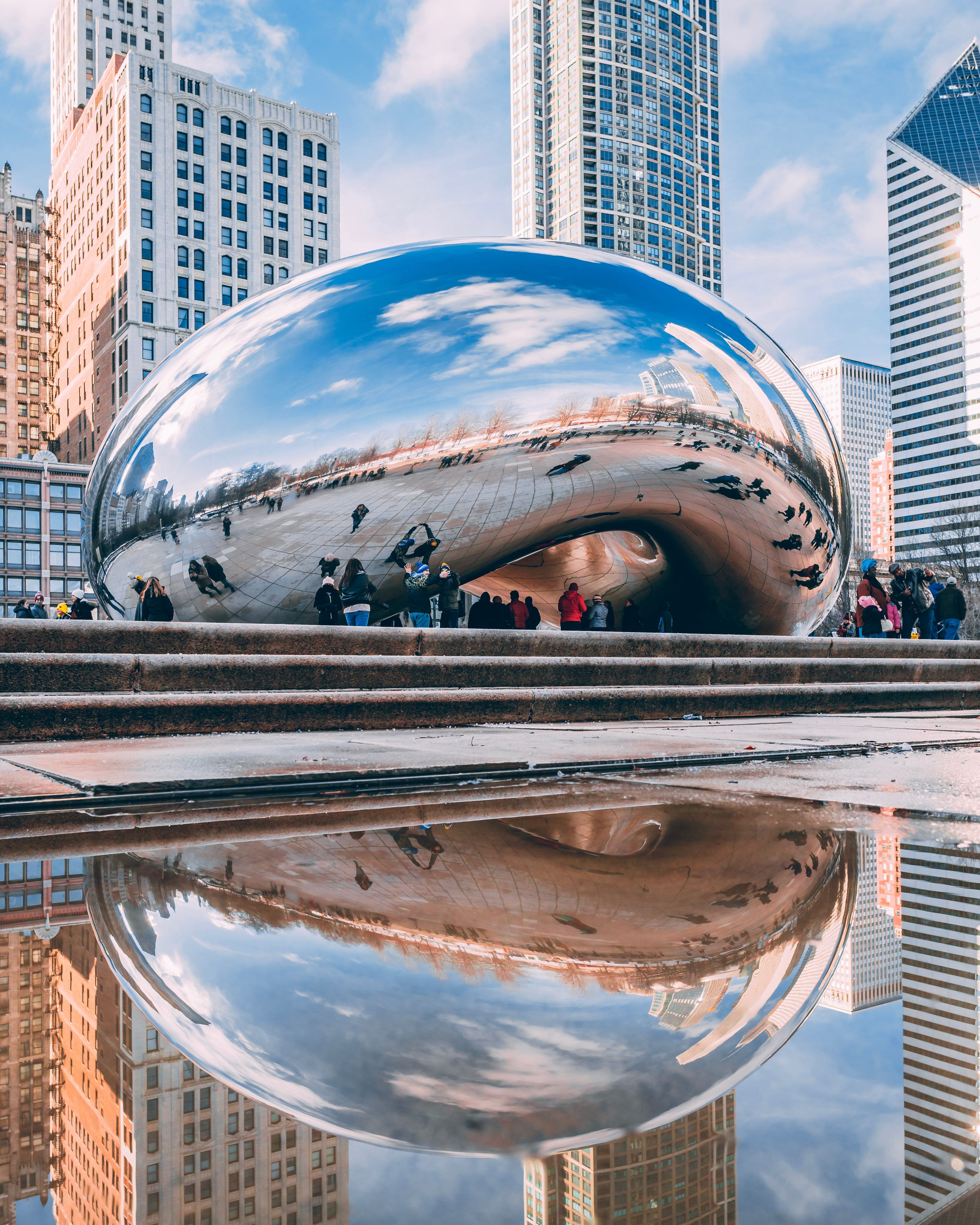 A vertical image of tourists looking at the bean in Chicago, IL