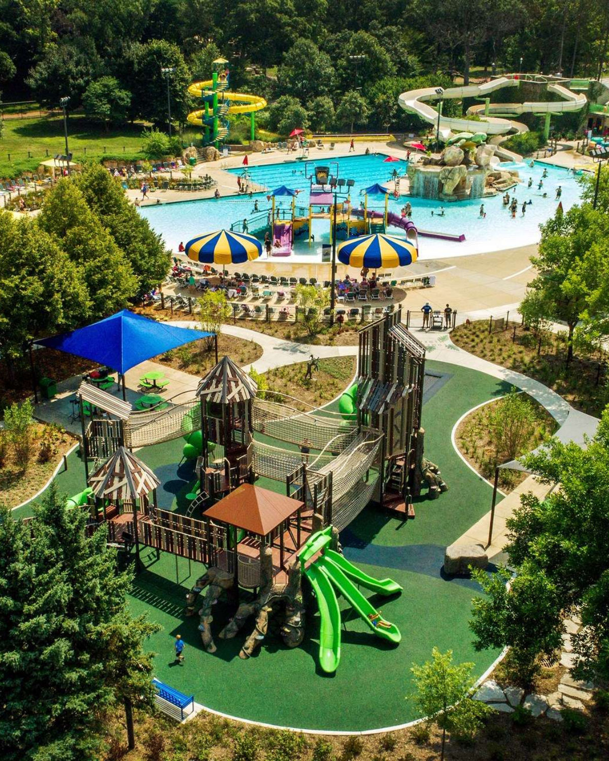 Aerial view of Turtle Splash Water Park in West Chicago, Illinois, showing a large zero-depth entry pool with colorful water play structures and slides, surrounded by a castle-themed playground with bright green slides and towers.