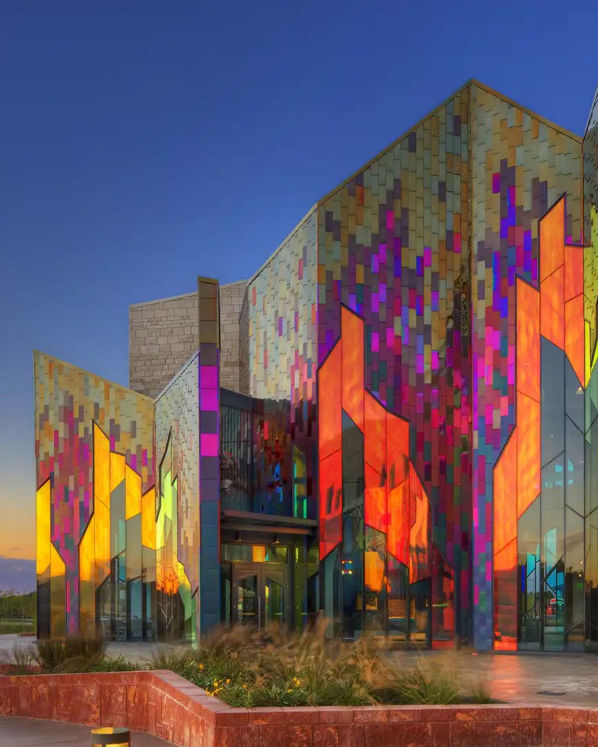 The striking colorful geometric glass facade of the Museum at Prairiefire in Overland Park, Kansas glowing with vibrant orange, red, and purple hues
